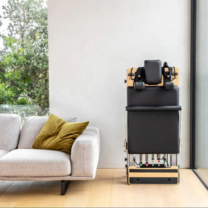 Pilates reformer folded in the corner of a living room.