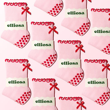 Pattern of pink socks with red hearts and bows, branded 'elliosa', on a white background.
