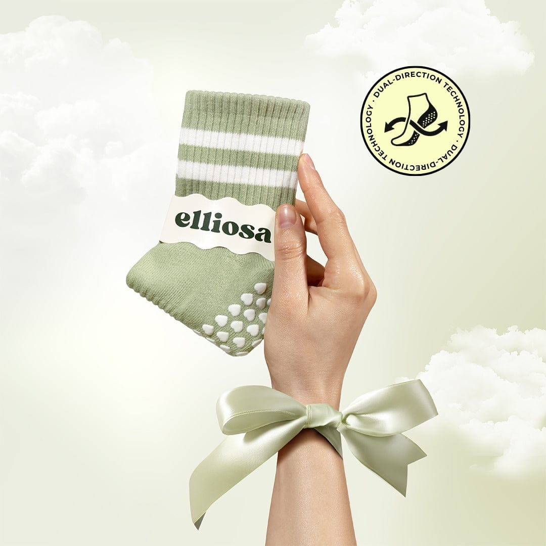 Hand holding a green sock with white stripes and 'elliosa' branding, against a light background.