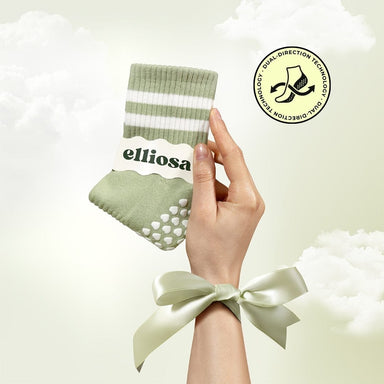 Hand holding a green sock with white stripes and 'elliosa' branding, against a light background.
