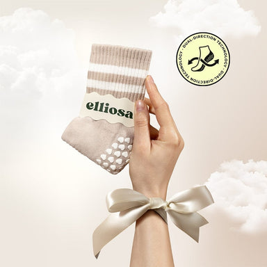 Hand holding a pair of beige socks with a visible brand label on a light background