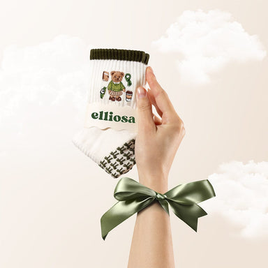 Hand holding a branded product with a bow, on a light background