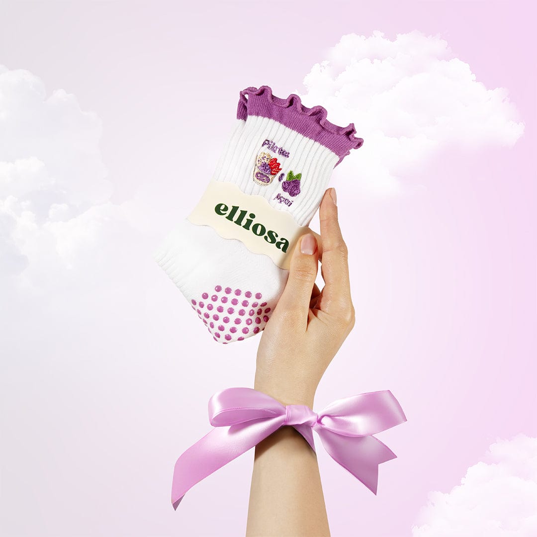 Hand holding a pack of socks with 'elliosa' branding against a light pink background