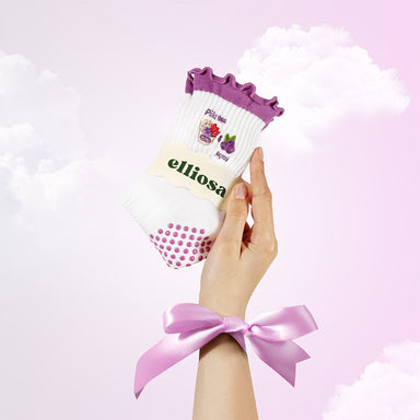 Hand holding a pack of socks with 'elliosa' branding against a light pink background