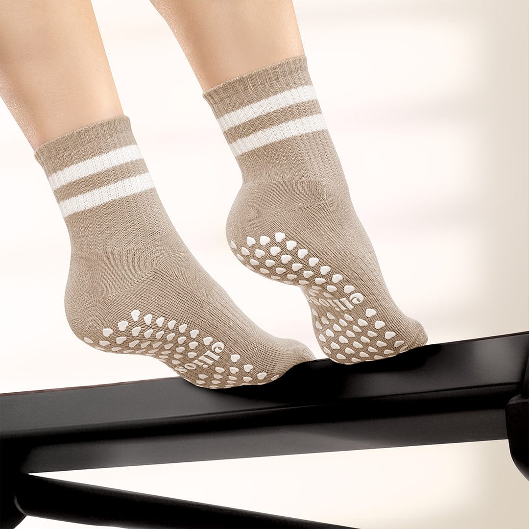 Beige socks with white stripes and textured sole on a neutral background