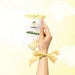 Hand holding a white product sock with yellow lemons and with the word 'sunkissed' with 'elliosa' branding against a light yellow background. There are yellow lemon shaped grips on the sole.