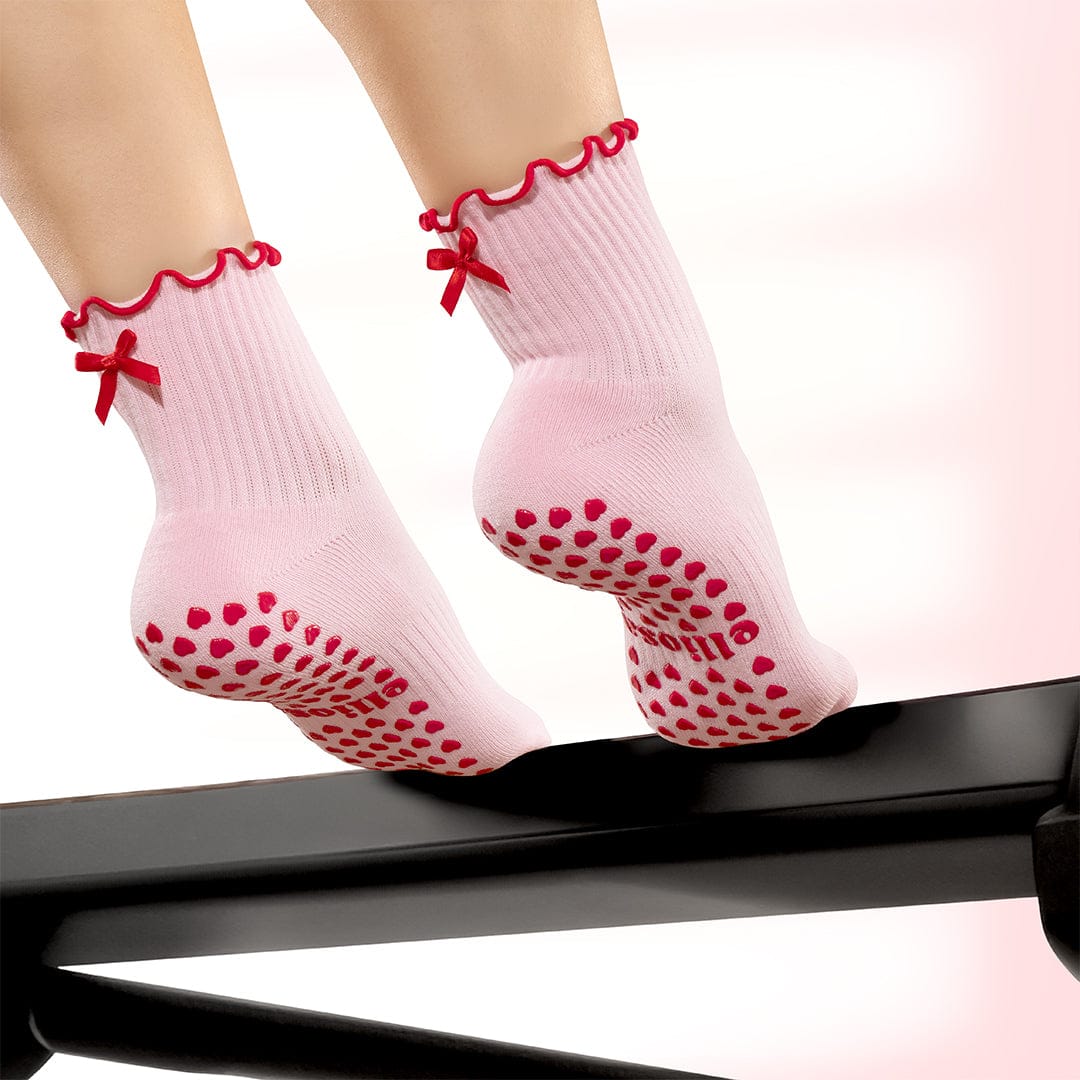 Pink socks with red bows and heart patterns on a white background