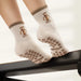 White socks with brown paw print grips on the sole and puppies and the words 'puppy pilates' embroidered. 
