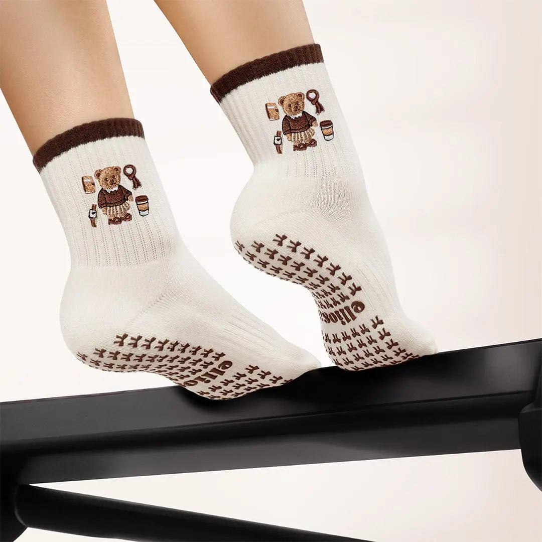 White socks with brown teddy bear design and brown bow shaped grips on the soles.