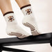 White socks with brown teddy bear design and brown bow shaped grips on the soles.