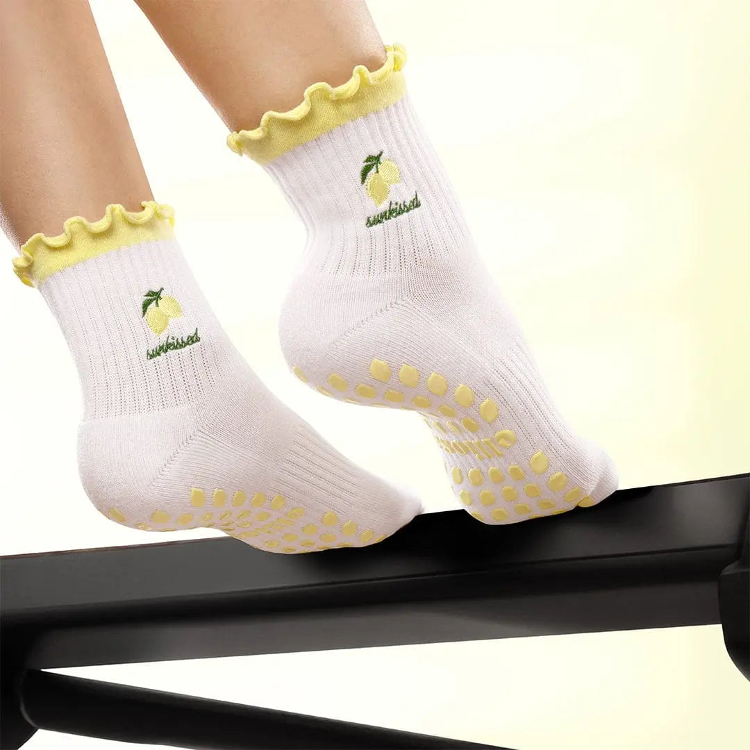 Feet in white socks with yellow lemons and with the word 'sunkissed' in green, with yellow lemon shaped grips on the sole.