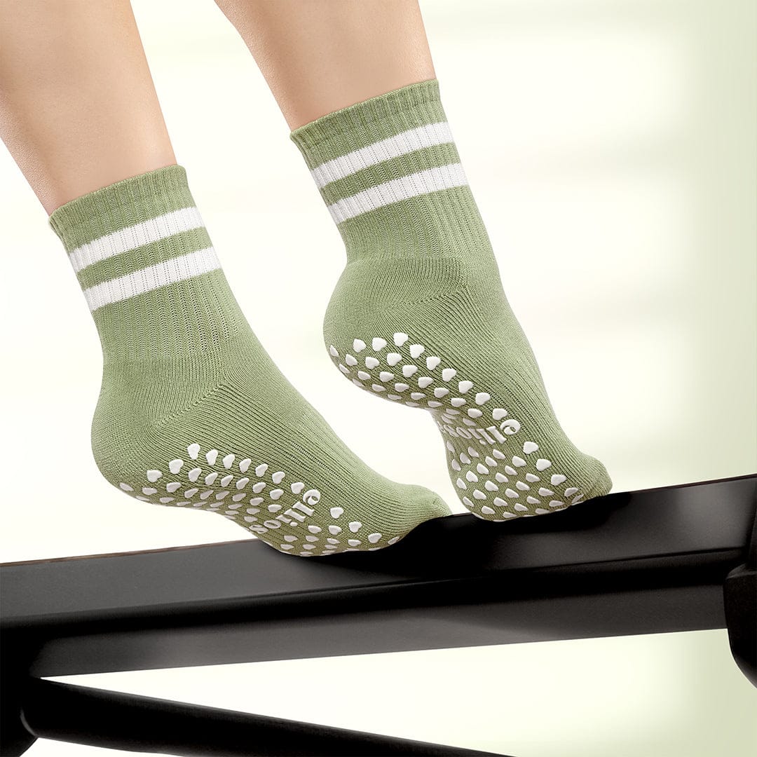 Green socks with white stripes and textured sole on a neutral background