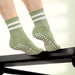 Green socks with white stripes and textured sole on a neutral background