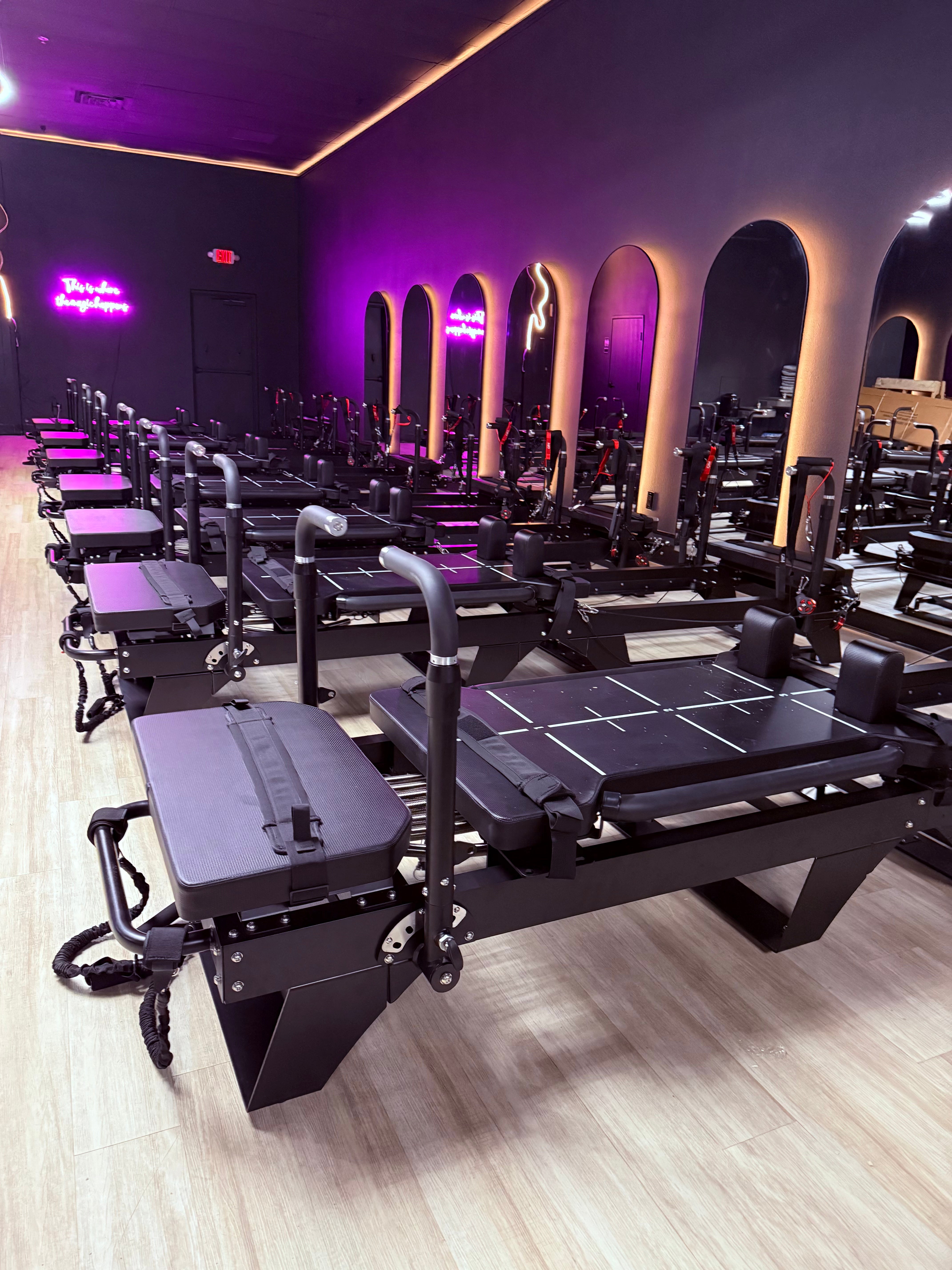 Dark Pilates studio showing 7 Core Collab Sculptformers in black in front of arched mirrors.
