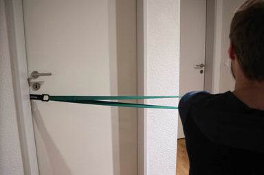 Person using the blackroll hook attached to the door, with a resistance band.