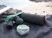 2 foam rollers, a duomassage ball and 2 resistance bands on a towel at the beach.