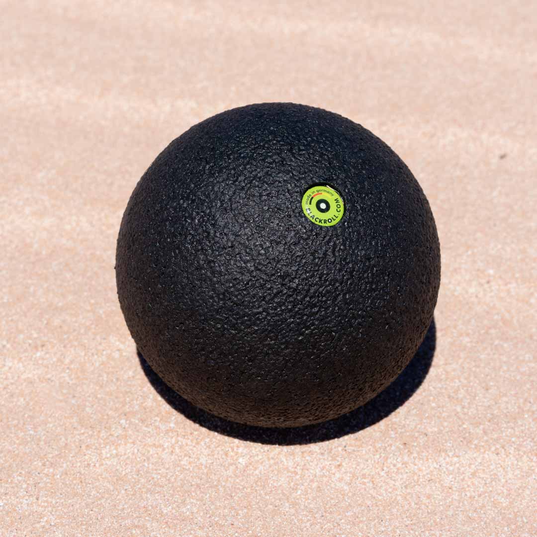 Black blackroll massage ball on the sand.
