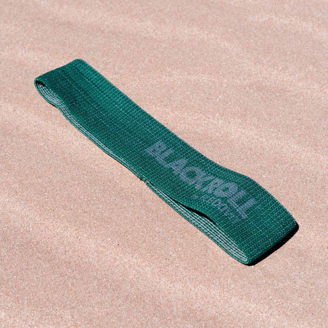 Green booty resistance band on the sand.