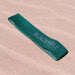 Green booty resistance band on the sand.