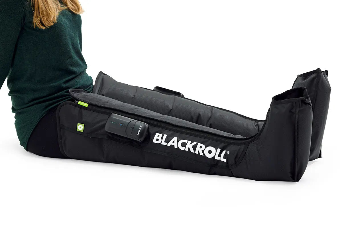 Blackroll compression boots 2.0 shown on woman sitting down with white background.