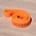 Orange blackroll resistance band rolled up on the sand.