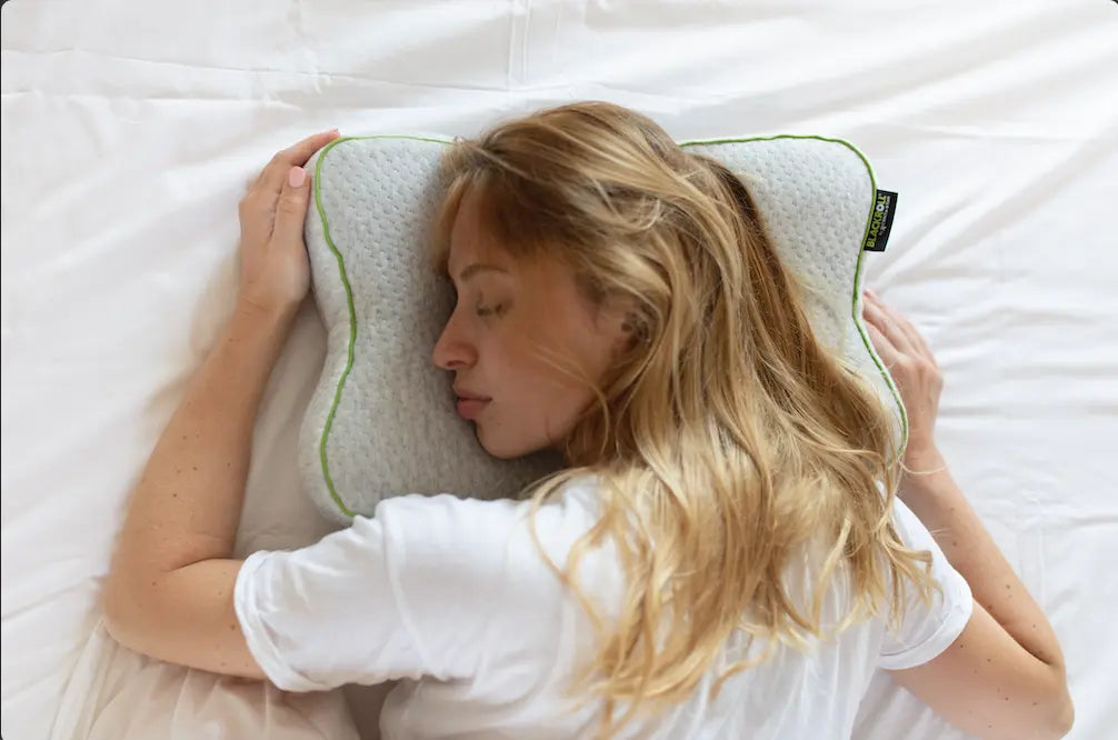 Woman sleeping on her stomach using a Blackroll pillow.