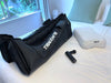 Blackroll recovery boots on the bed next to a fascia gun and recovery pillow.