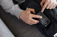 Person using a black electronic device showing the power buttons for the Blackroll Recovery Boots 2.0