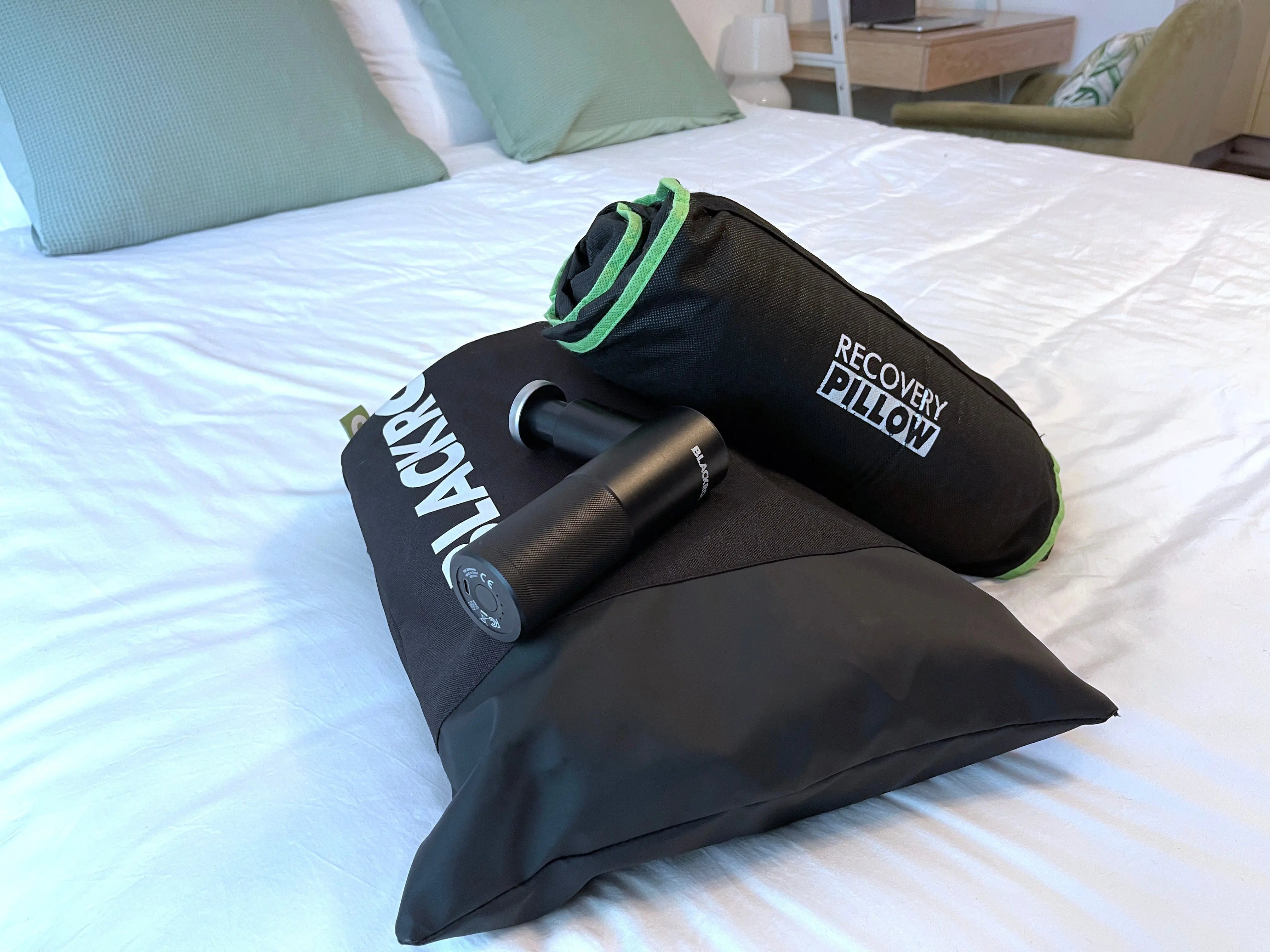 Blackroll recovery pillow rolled up and in its travel bag, fascia gun and a bag containing recovery boots 2.0.