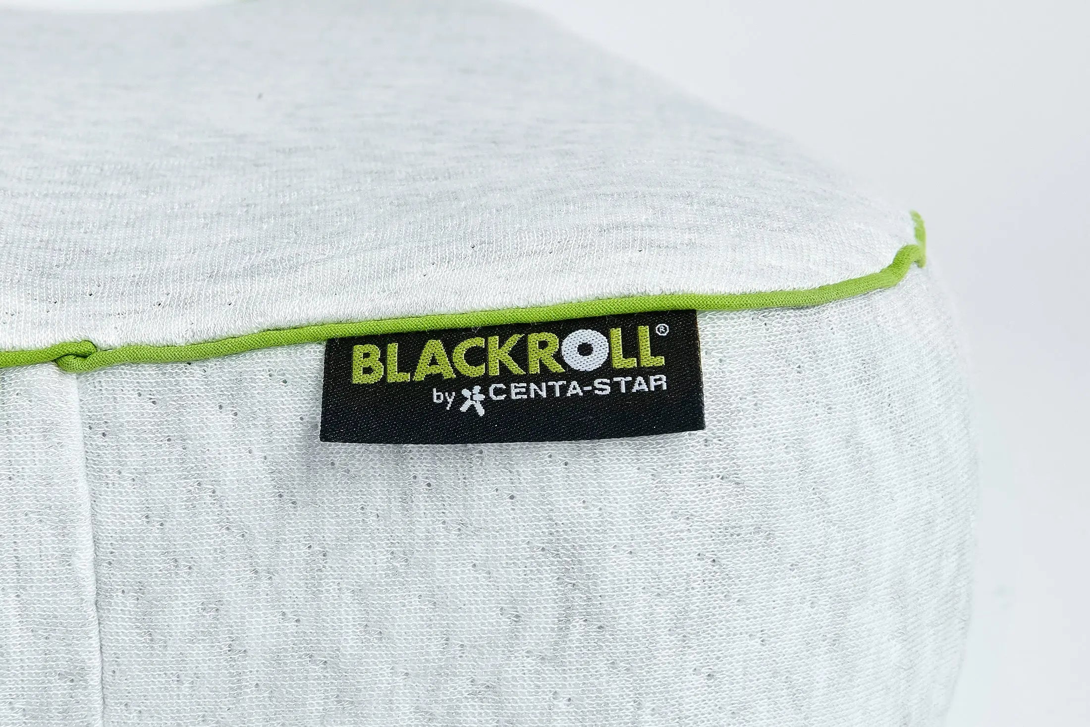 Close up of the Blackroll recovery pillow showing white pillowcase with green border and the Blackroll tag.