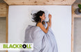 Woman sleeping on a bed using the Blackroll pillow with the brand logo visible.