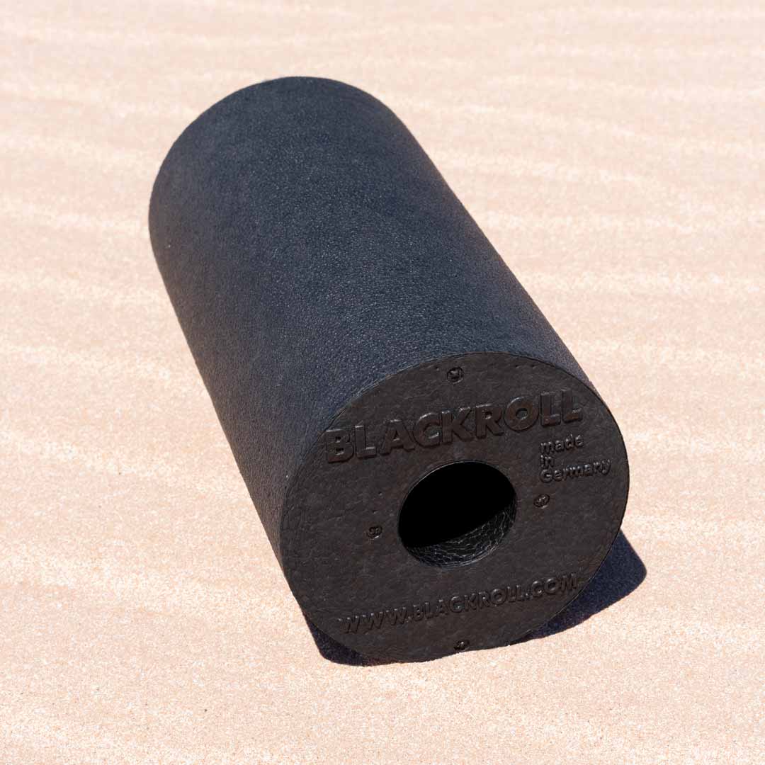 Black blackroll standard foam roller on the sand.