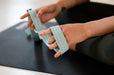 Close up of the hands of a person holding a Blackroll stretch band resistance band on a Pilates mat.