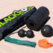 Blackroll fitness tools including a foam roller, massage ball, peanut ball and resistance bands on the sand.