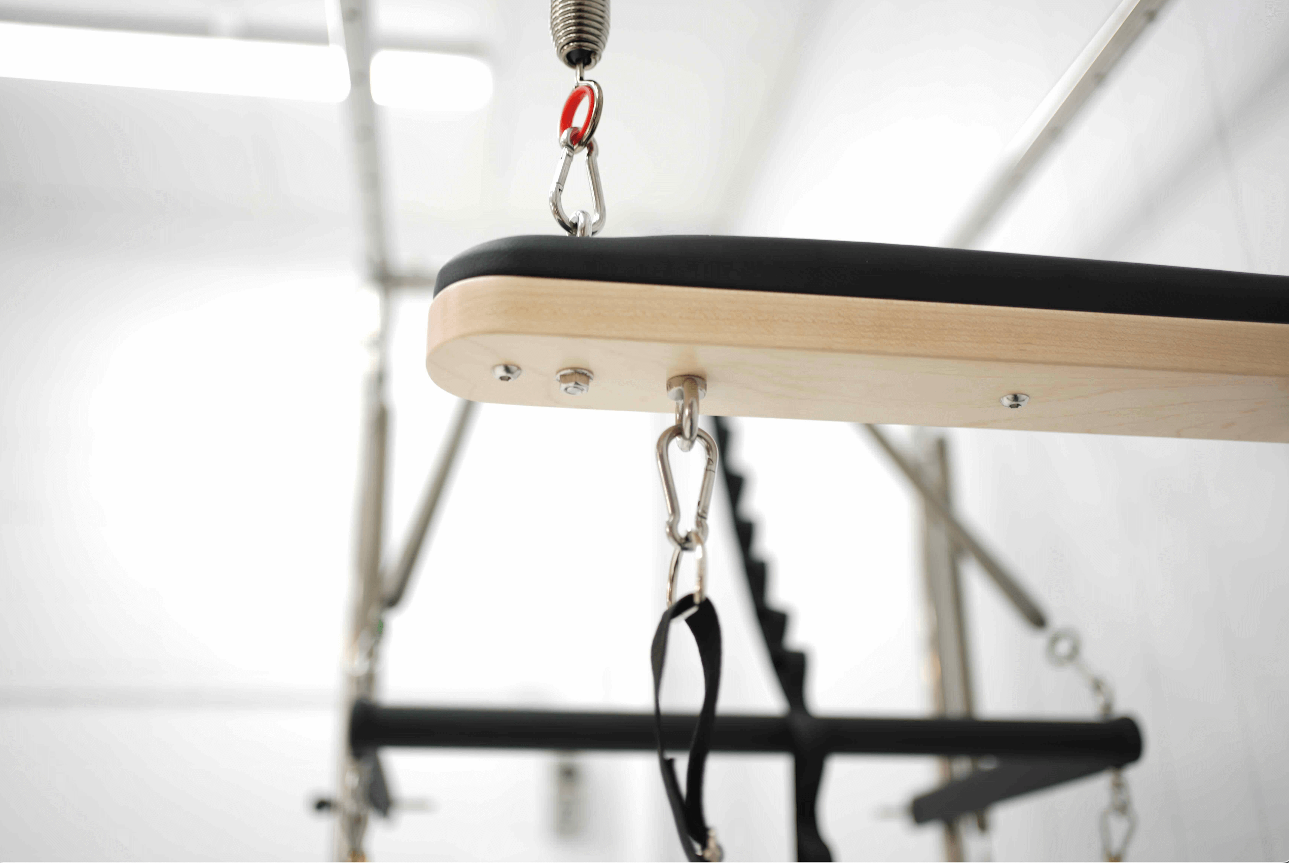 Close up of trapeze attachment on queen reformer showing carabiners.