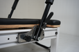 Close up of the foot bar adjuster of the Core Collab queen Pilates reformer with black upholstery and black footbar.