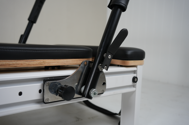 Close up of the foot bar adjuster of the Core Collab queen Pilates reformer with black upholstery and black footbar.