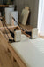 Close up of the carriage of a Core Collab Foldable Eco Pilates reformer with white upholstery in a home setting.