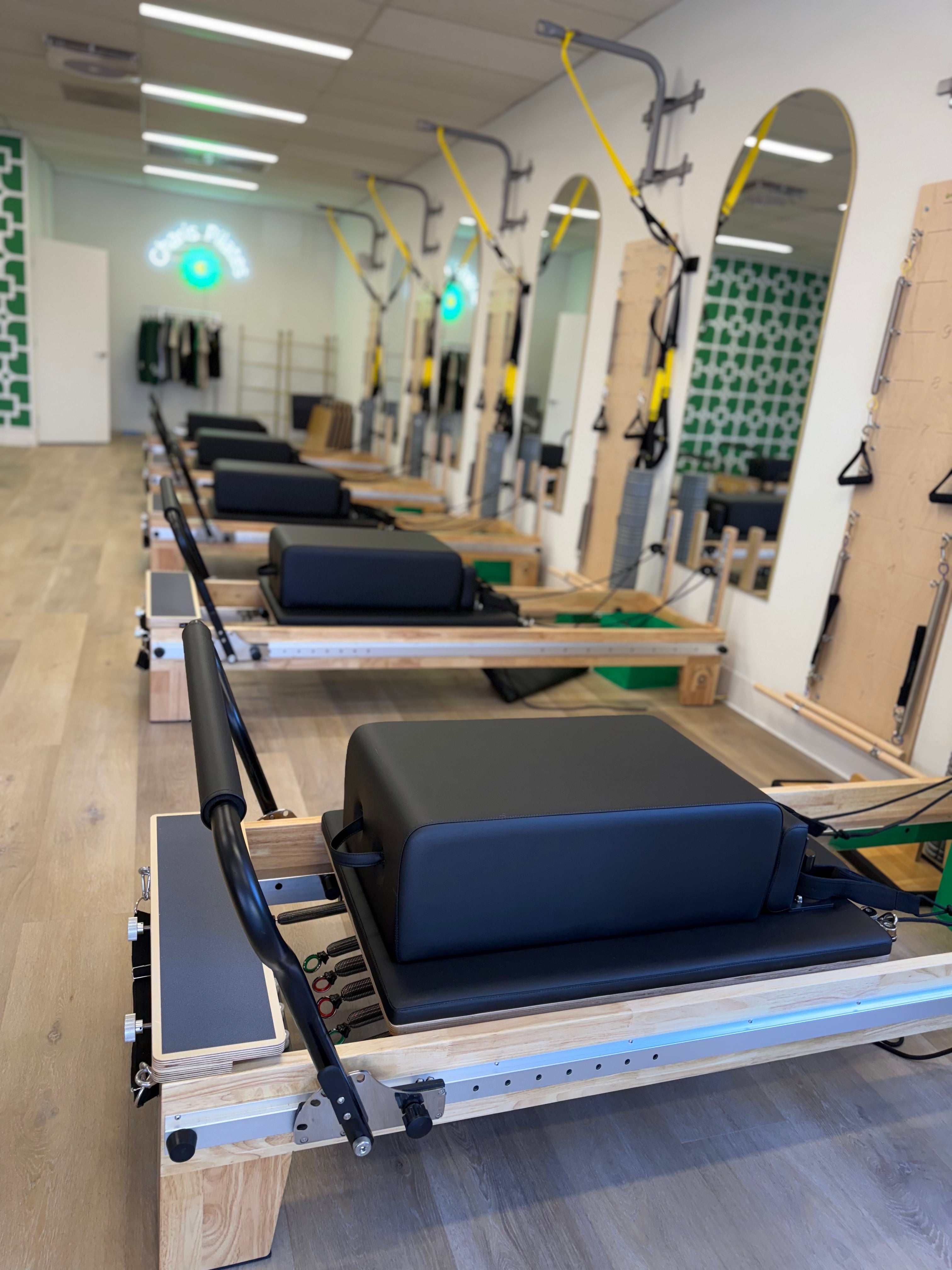 Pilates studio fitted with 5 Core Collab Eco Studio full track Pilates reformers with wooden frame and black upholstery, with the springs visible and sitting box on top of the reformer carriage.