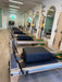 Pilates studio fitted with 5 Core Collab Eco Studio full track Pilates reformers with wooden frame and black upholstery, with the springs visible and sitting box on top of the reformer carriage.