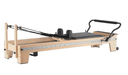 Core Collab Eco Studio Full Track Pilates reformer on an angle showing the wooden frame with track along the length of the reformer bed, and black upholstery.