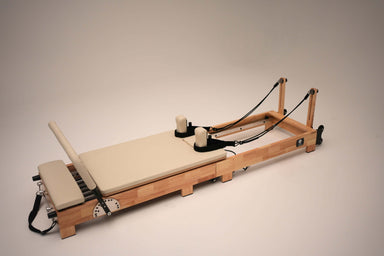 Angle view of the Core Collab Foldable Eco Pilates Reformer in beige, on a beige background.