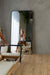 Woman lunging on the Core Collab Foldable Eco Pilates reformer in beige while looking in the mirror.