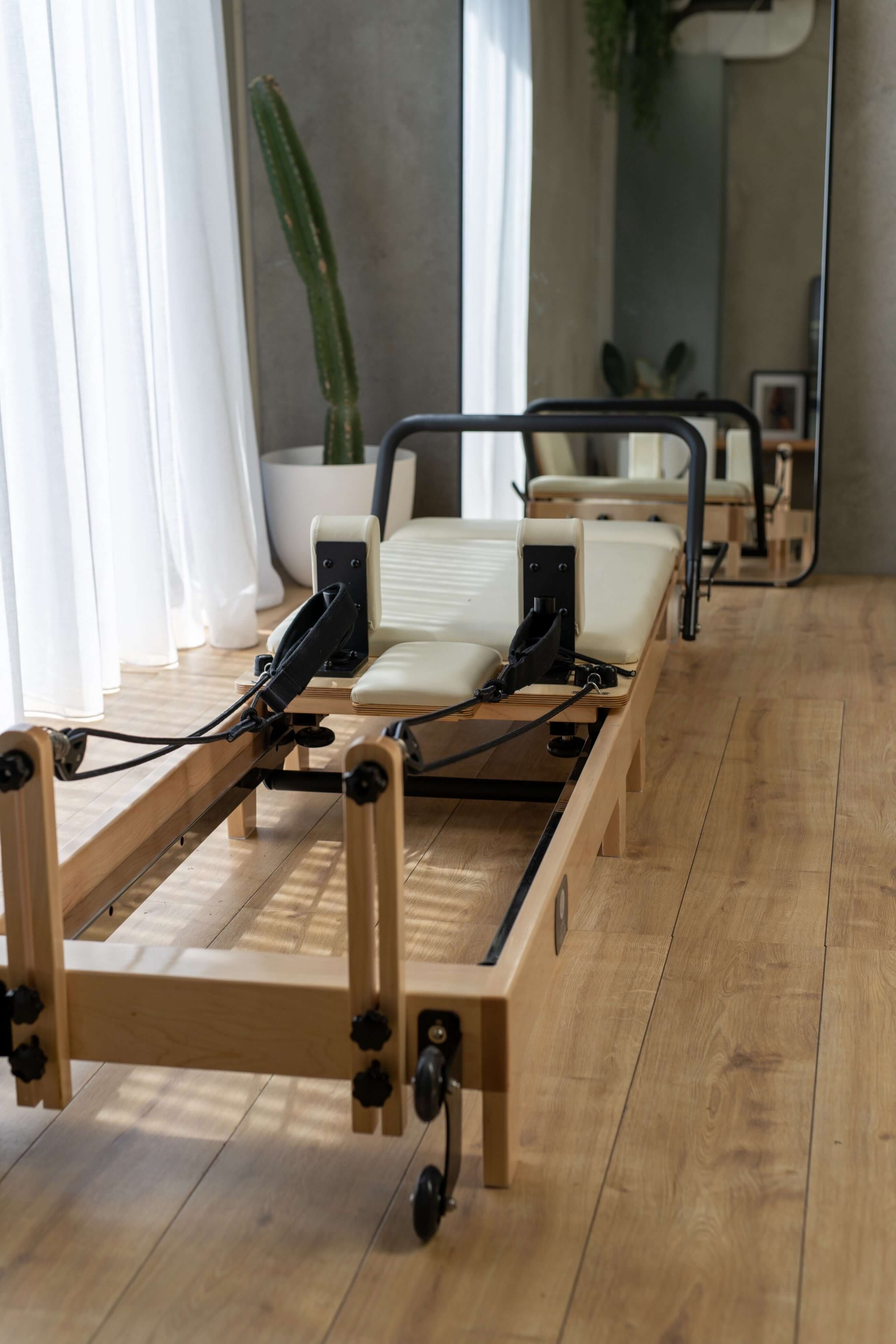 End view of the Core Collab foldable eco Pilates reformer in a studio setting in front of a mirror.