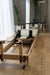 End view of the Core Collab foldable eco Pilates reformer in a studio setting in front of a mirror.