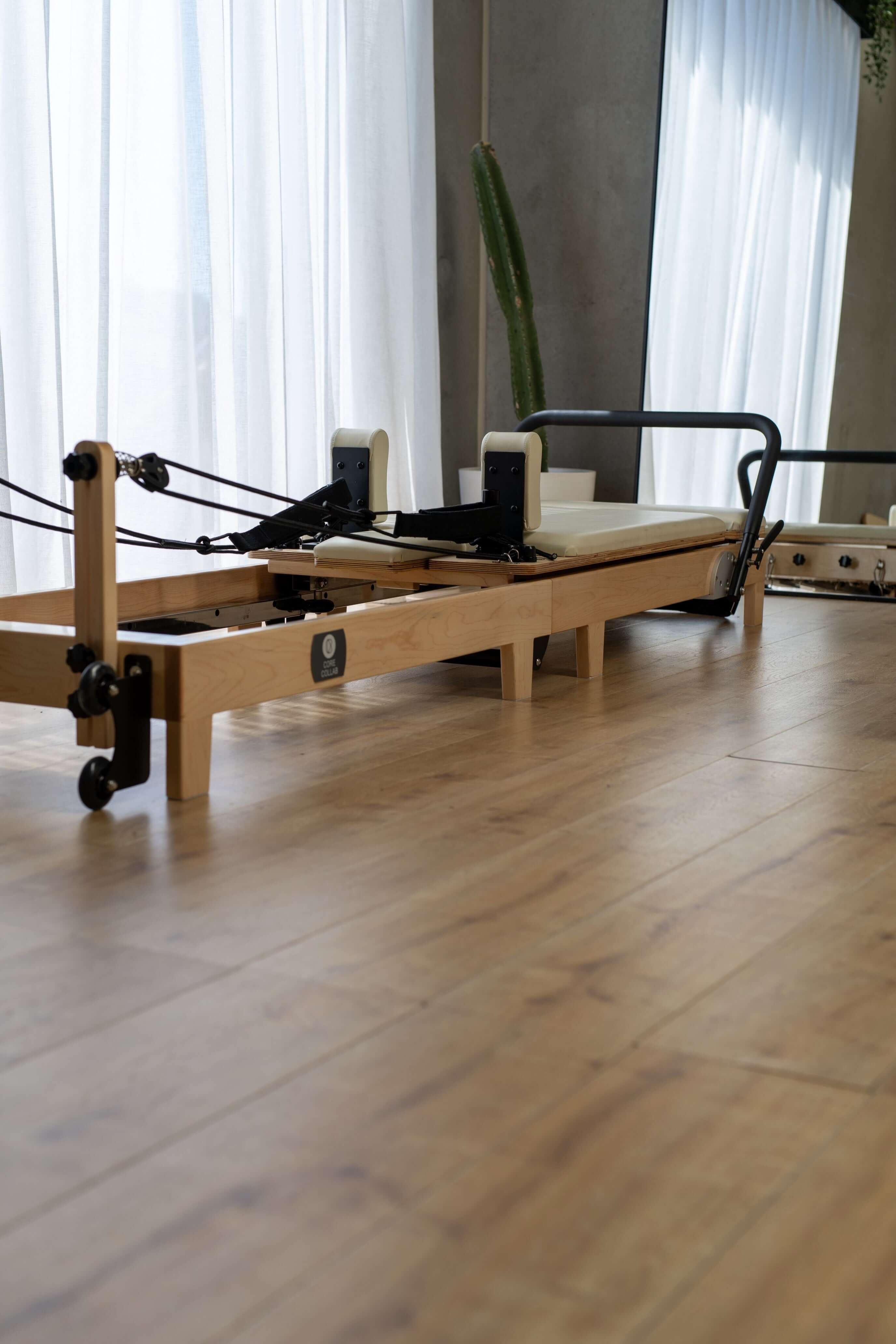 The Core Collab foldable eco Pilates reformer in a studio setting in front of a mirror.