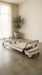Core collab queen 2.0 reformer in white with beige upholstery in a home studio setting with concrete floor and a plant in the corner.