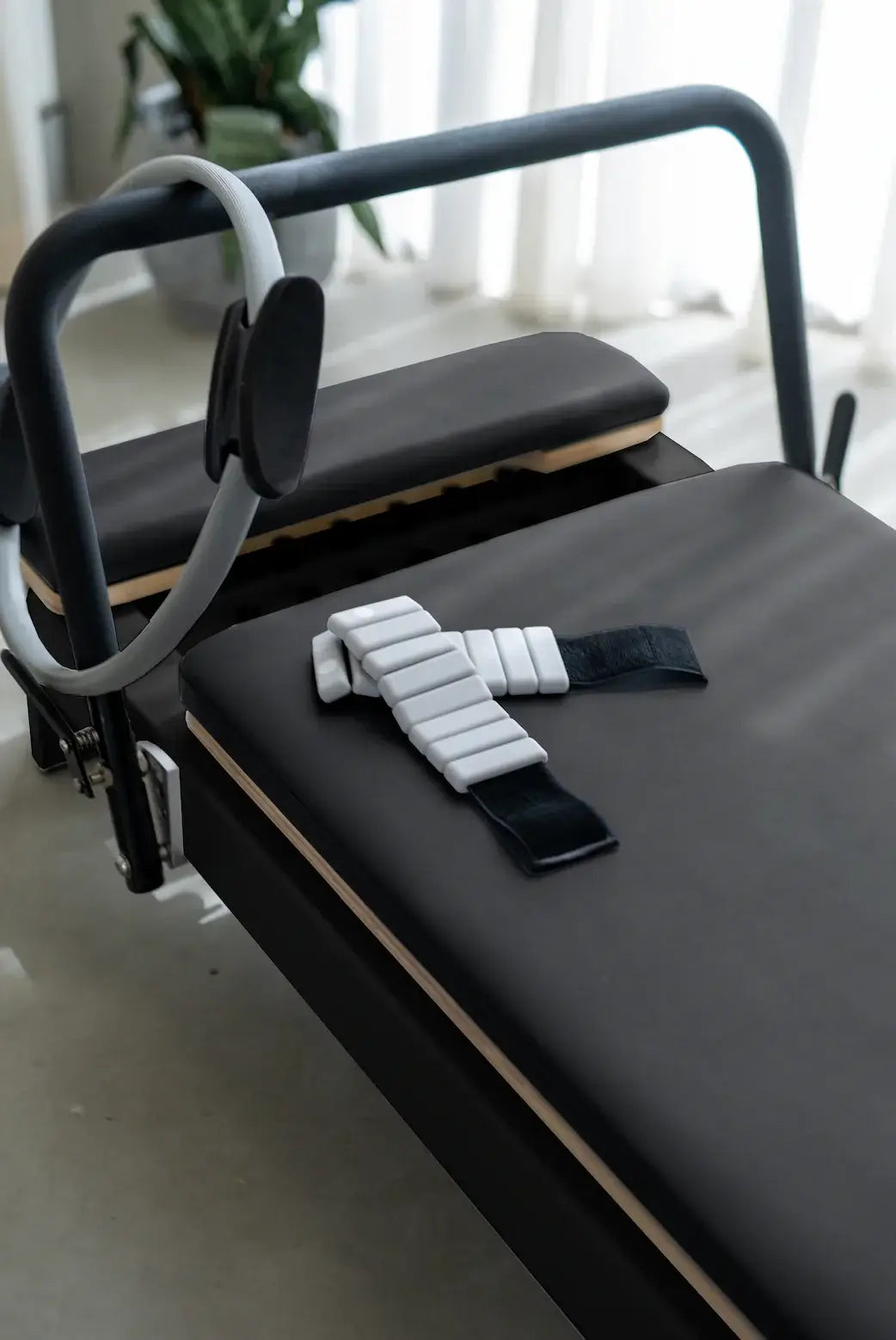 Core Collab Queen Studio Pilates reformer in black with charcoal upholstery, with a magic circle and ankle weights.
