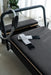 Core Collab Queen Studio Pilates reformer in black with charcoal upholstery, with a magic circle and ankle weights.