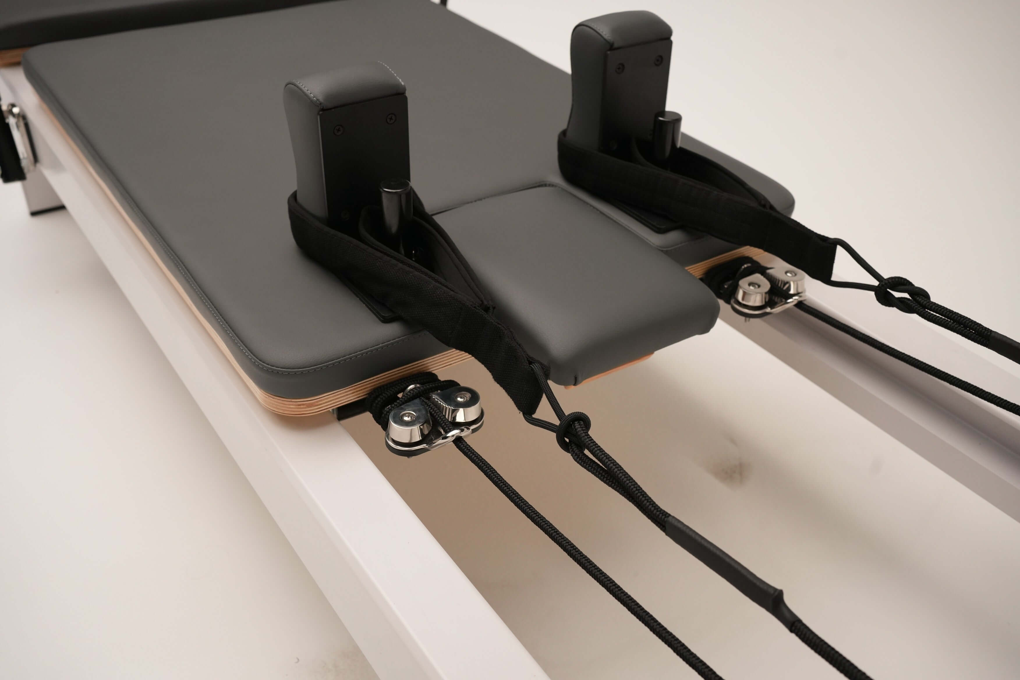 Close up of the Core Collab Queen Studio Pilates reformer showing the head cushion, shoulder rests and straps.